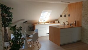 Une cuisine moderne avec un îlot central en bois, des meubles blancs et une lucarne.