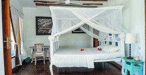 A bedroom with a four-poster bed, a small table with a lamp, and a chair.
