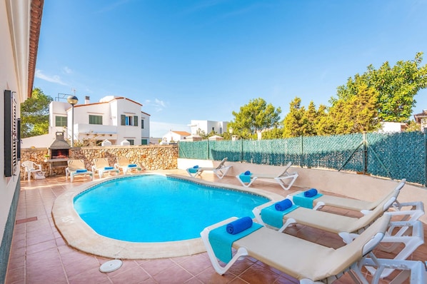 A swimming pool with lounge chairs and a stone wall.