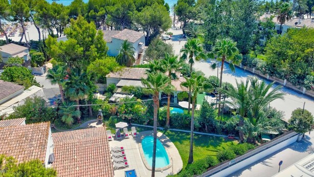 Un resort con piscina, palme e vista sul mare.