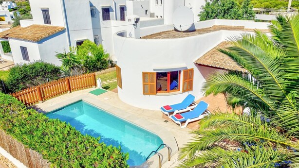 Una villa moderna con piscina, tumbonas y vistas del entorno.