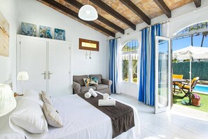 Ein Schlafzimmer mit einem Bett, einer Couch und Blick ins Freie.