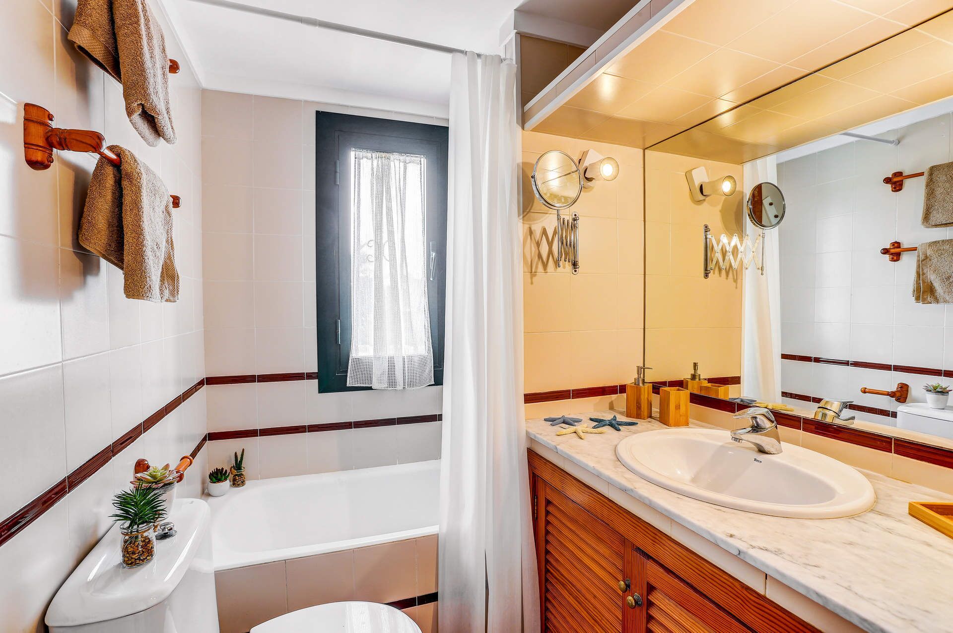 Un baño con bañera, dos lavamanos, un espejo grande y toalleros.