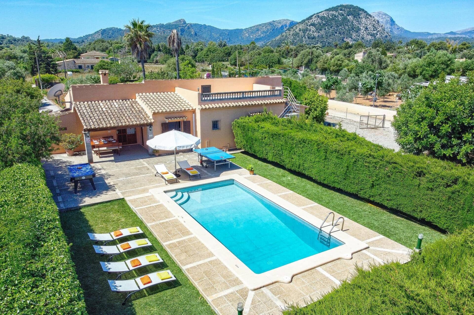 Eine Villa mit Swimmingpool, Sitzgelegenheiten im Freien und Blick auf Berge.