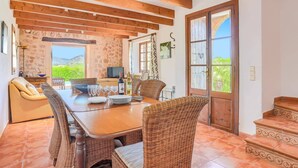 A dining area with a wooden table, wicker chairs, and a view of the outdoors. - Villa Can Xanet de Baix by Villa Plus (Mallorca)