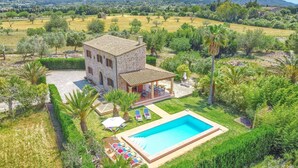 A stone villa with a swimming pool, surrounded by lush greenery and mountains in the background. - Villa Can Xanet de Baix by Villa Plus (Mallorca)