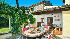 Un'area pranzo all'aperto con un tavolo rotondo, sedie e un edificio in pietra sullo sfondo.