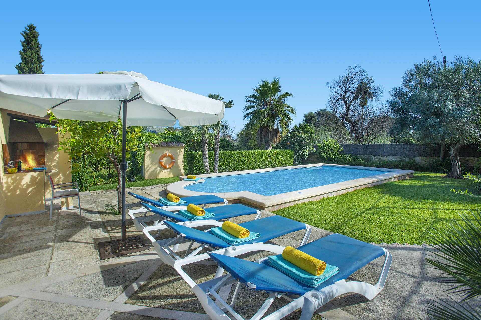 Un espace piscine avec des chaises longues, un barbecue et une bouée de sauvetage fixée au mur.