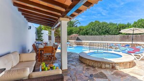 Un espacio al aire libre techado con piscina, sillas de descanso y una mesa de comedor con alimentos para el desayuno.