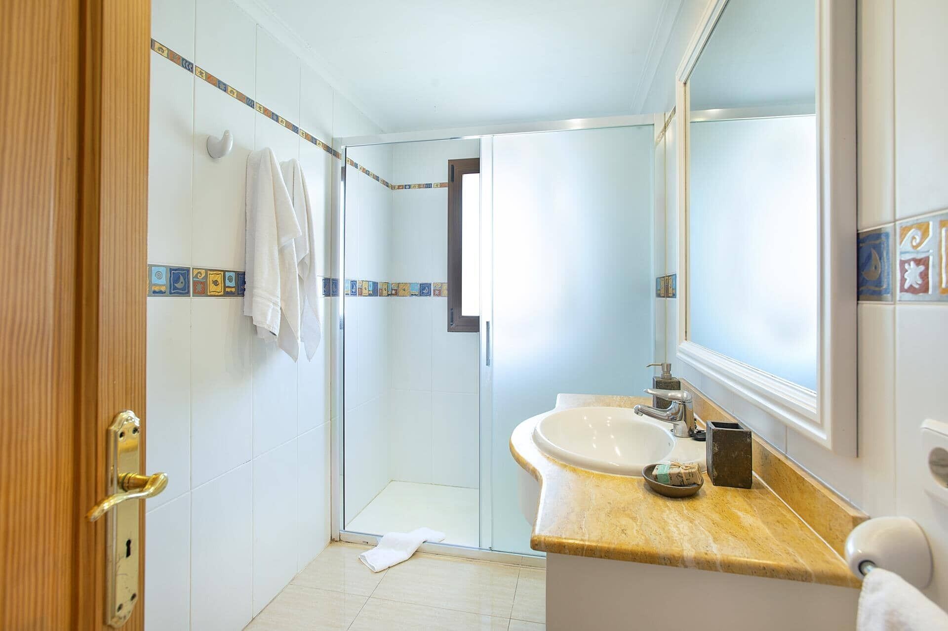 Ein Badezimmer mit Dusche, Waschbecken und Spiegel.