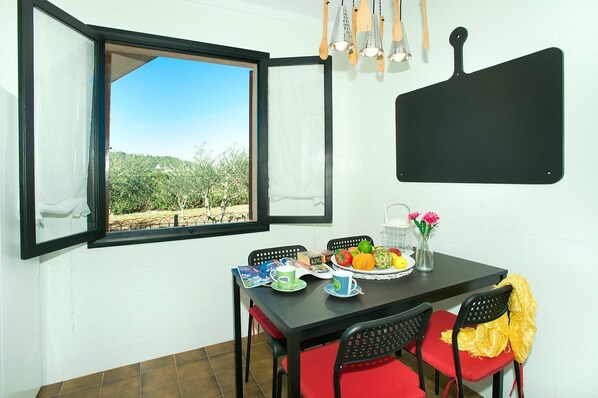 A dining area with a table set for two, a window with an open view, and a blackboard on the wall. - Villa Guaita II by Villa Plus (Mallorca)