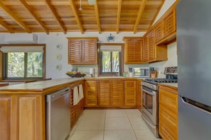 Une cuisine avec des meubles de rangement en bois, un lave-vaisselle, une cuisinière et un réfrigérateur.