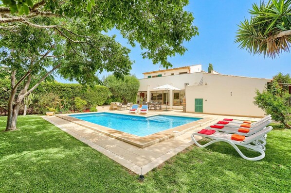 Une piscine avec des chaises longues et un espace patio.