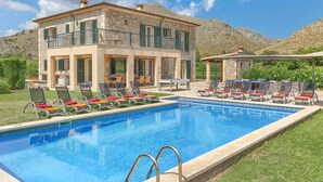 Un bâtiment en pierre de deux étages, doté d’une piscine et d’un espace extérieur aménagé pour s’asseoir.