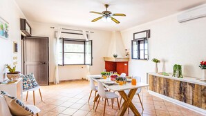 A dining area with a wooden table, white chairs, and a ceiling fan. - Villa Guglielmo by Villa Plus (Costa Merlata)