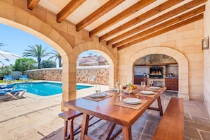 An outdoor dining area with a pool and stone walls.
