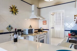 A kitchen with a microwave, oven, and wine glasses on the counter.