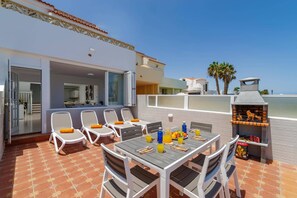 An outdoor patio with a dining table, chairs, and a grill.