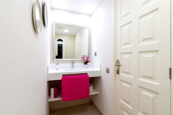 A bathroom with a white sink, a mirror, a pink towel, and a door. - Villa Bella Vista by Villa Plus (Corralejo)