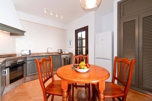 A compact kitchen with a dining table, chairs, and a bowl of fruit. - Villa Denise by Villa Plus (Tías)