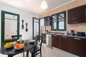 A modern kitchen with a dishwasher, a coffee maker, and a dining area with a table set for breakfast.