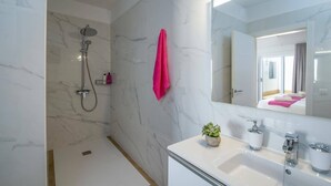 A modern bathroom with a shower, a sink, a mirror, and a potted plant.