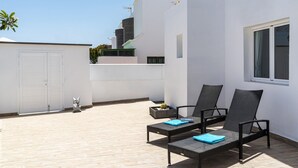 A rooftop terrace with two black wicker lounge chairs, a small table, and a potted plant. - Villa Deluxe by Villa Plus (Puerto del Carmen)