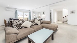 A modern living room with a beige sectional sofa, a glass coffee table, and a view of the beach through large windows. - Villa Deluxe by Villa Plus (Puerto del Carmen)