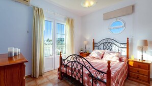 A bedroom with a bed, bedside tables, a window with curtains, a ceiling light, and a view of the outside.