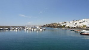 A marina with boats docked, a clear sky, and a hillside with white buildings.