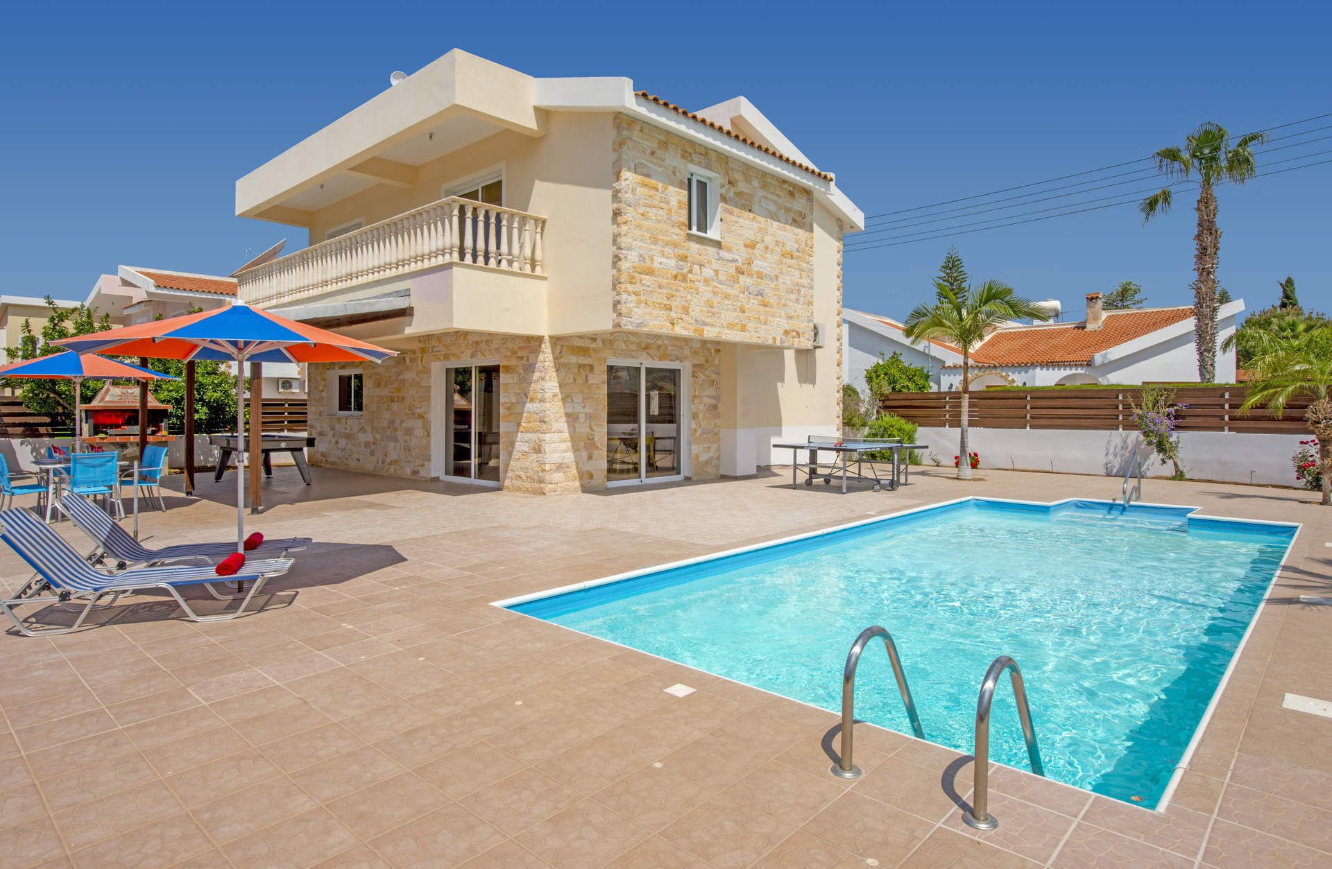 Una villa a due piani con piscina, area salotto esterna e patio.