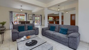 A spacious living room with two grey sofas, a coffee table, and a dining area with a table and chairs. - Villa Dione by Villa Plus (Peyia)