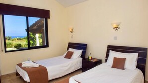 A hotel room with two beds, a large window with a view, and wall-mounted lamps. - Villa Elaia by Villa Plus (Poli Crysochous)