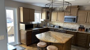 A modern kitchen with a large island, wooden cabinets, and stainless steel appliances. - Hillside View Times Two (Arroyo Grande)