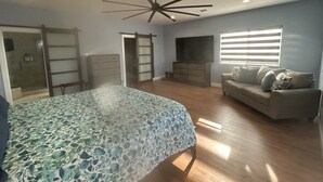 A bedroom with a bed, a dresser, a TV, a ceiling fan, and a window with blinds. - Hillside View Times Two (Arroyo Grande)