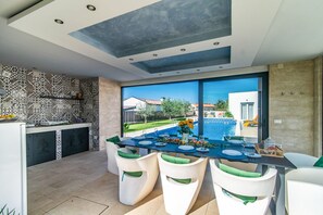 Eine moderne Küche mit Musterfliesen und einem Essbereich mit Blick auf einen Pool.