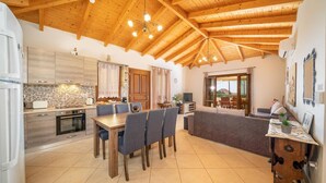 Un grand espace de vie doté d’un plafond en bois, d’une table à manger avec des chaises, d’un canapé et d’un téléviseur.