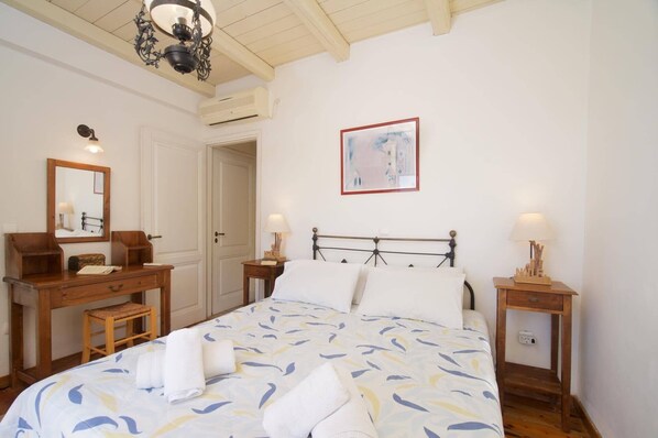 Una camera da letto con un letto, due comodini, una cassettiera, uno specchio e un lampadario.