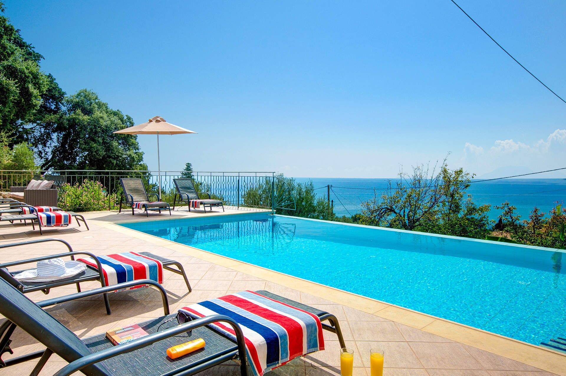 Zona de piscina con sillones y vistas al mar.