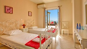 A hotel room with two beds, a small desk, and a view of the balcony. - Villa Chrissos by Villa Plus (Lourdata)