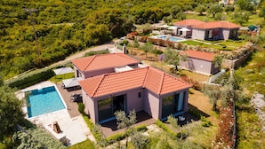 Una villa moderna con piscina, immersa nel verde e circondata da montagne.