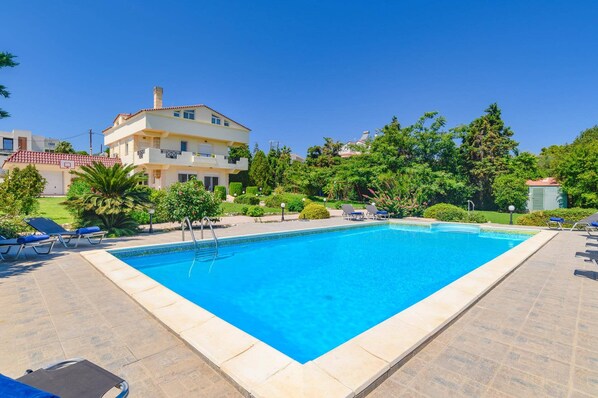 A rectangular swimming pool with a clear blue water surface, surrounded by a paved deck.