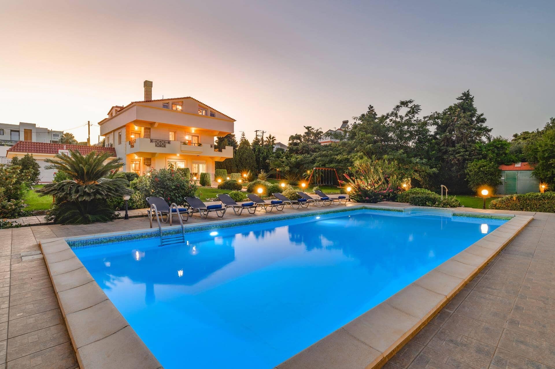 A swimming pool with lounge chairs and a building with multiple balconies in the background.