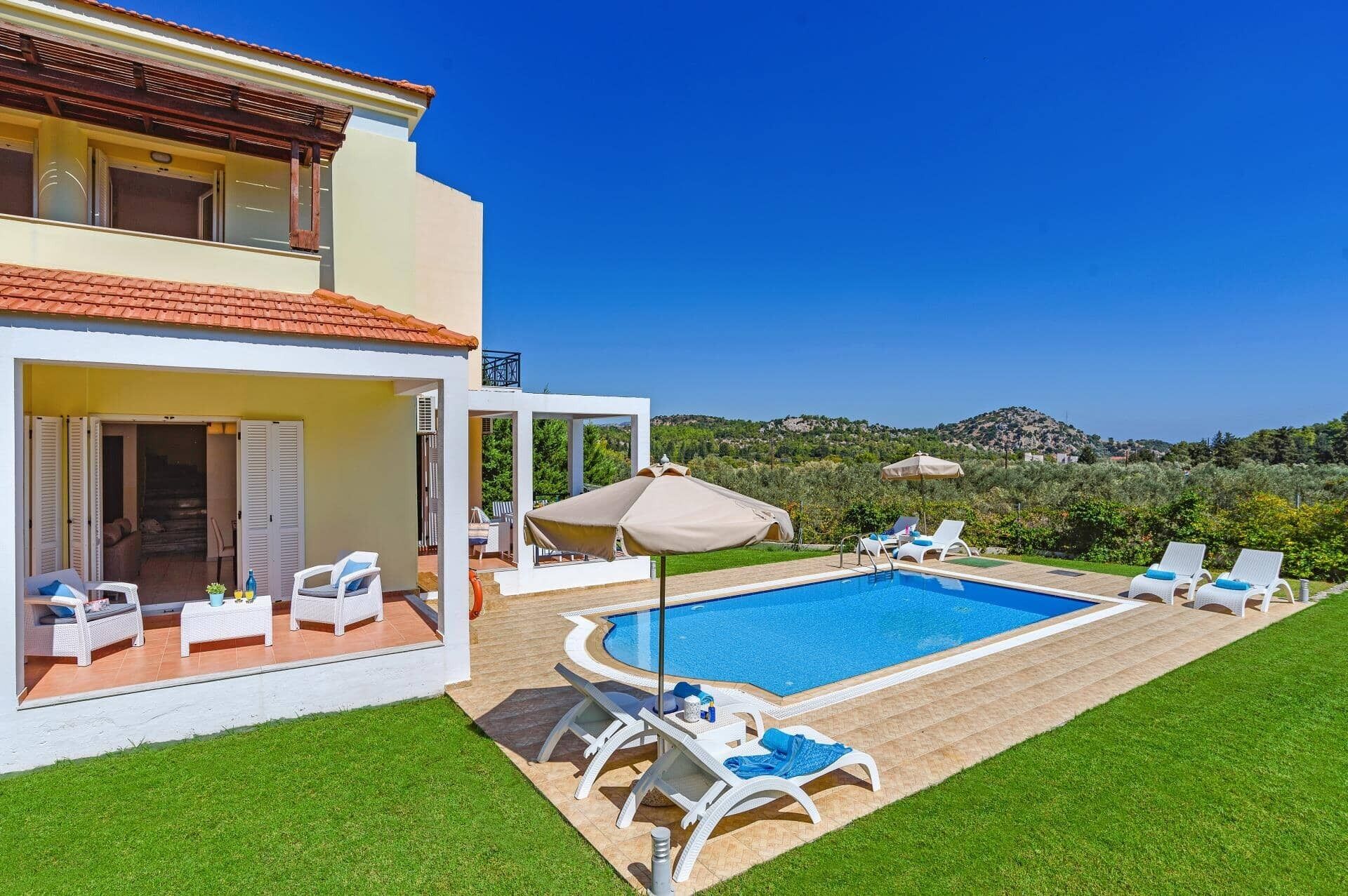 Una casa de dos pisos con piscina, mobiliario exterior y vistas a las colinas.