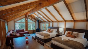 A cozy attic bedroom with a wooden ceiling, two beds, a sofa, and a dining table. - Sundance By Basecamp (Kananaskis)