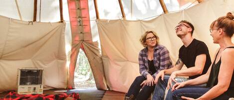 A tent with a bed, a heater, and a view of the outdoors.