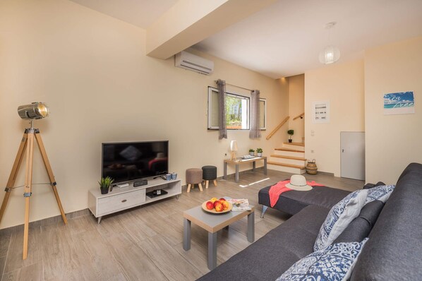 A modern living room with a TV, sofa, coffee table, and a telescope.