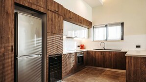 Une cuisine moderne avec des meubles en bois, un four encastré et un réfrigérateur en acier inoxydable.