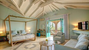 A bedroom with a four-poster bed, a sitting area with a sofa and armchairs, and a view through an open door to the outside. - Villa Amari by Villa Plus (Koridallos)