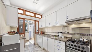 Une cuisine moderne avec des armoires blanches, une cuisinière en acier inoxydable et un dosseret carrelé.